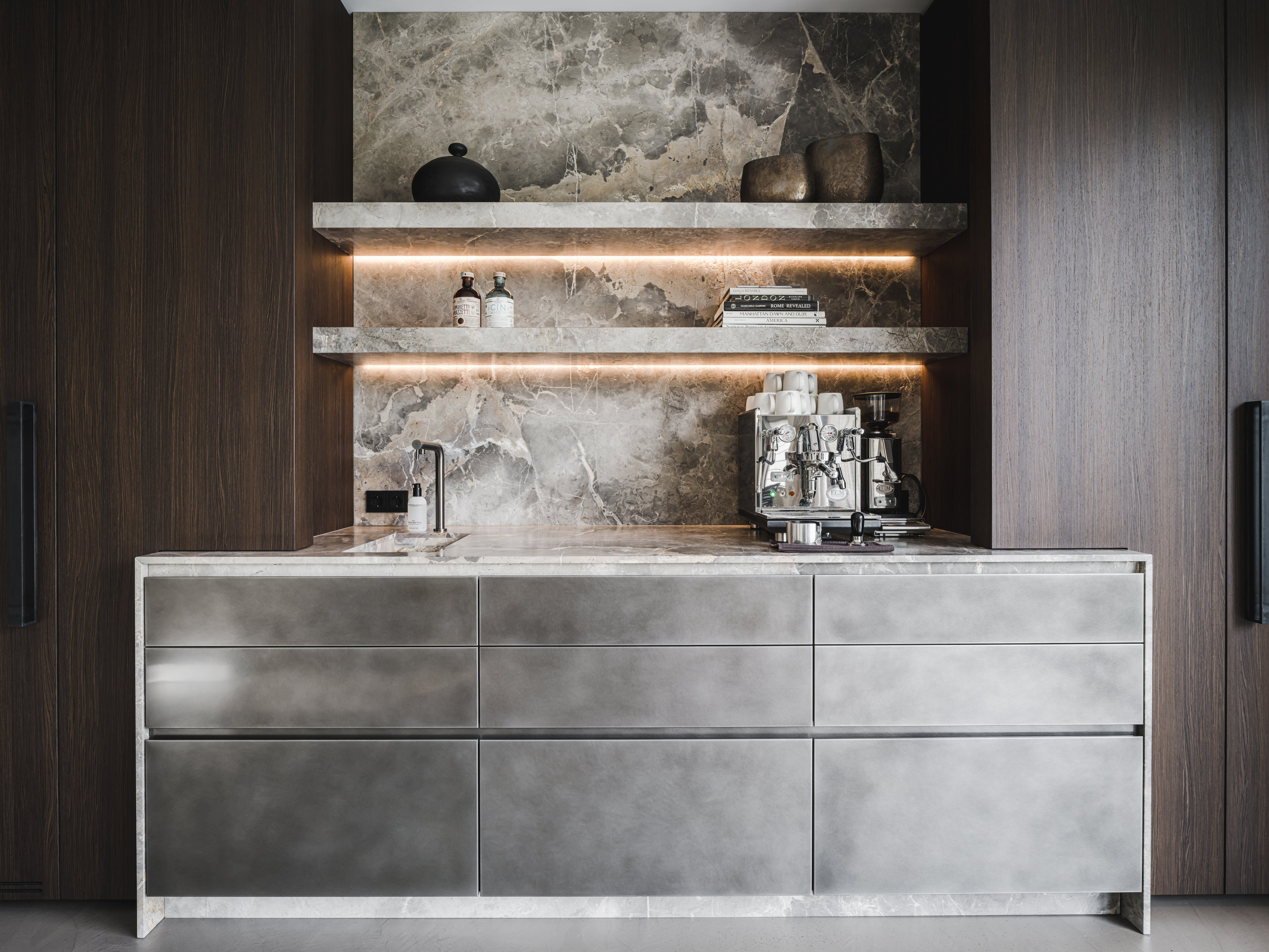 Koffiebar met natuurstenen wand, verlichte planken en espressomachine