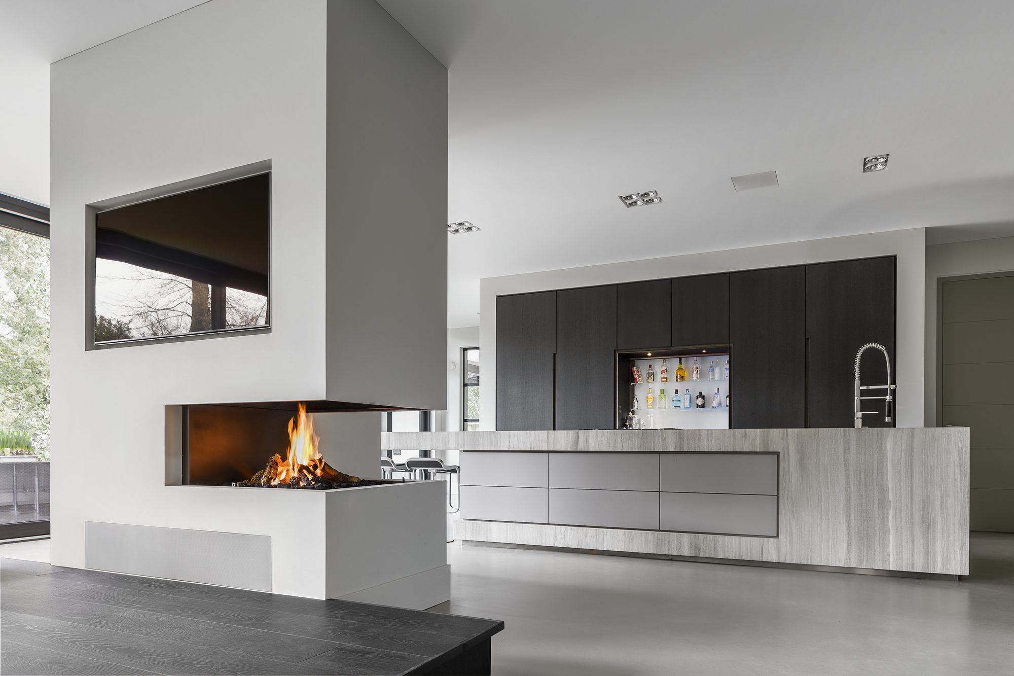 Open leefruimte met haard en grijze Culimaat keuken in woning van Bob Manders