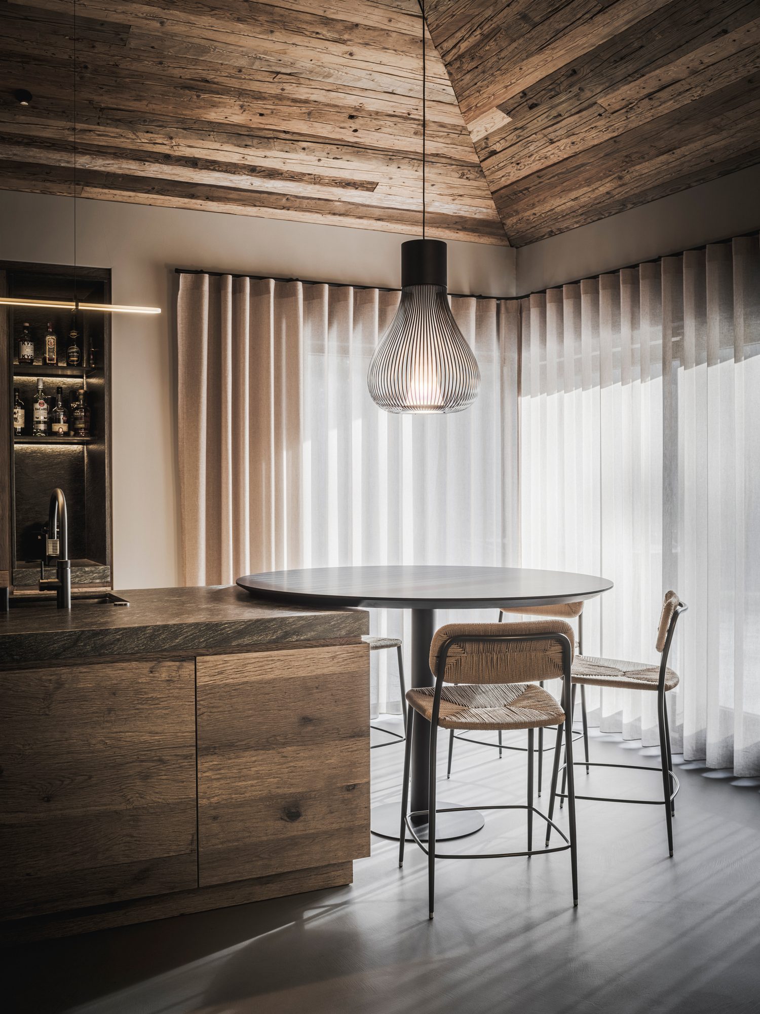 Bar met barkrukken aan het stenen keukeneiland met uitzicht op het bos