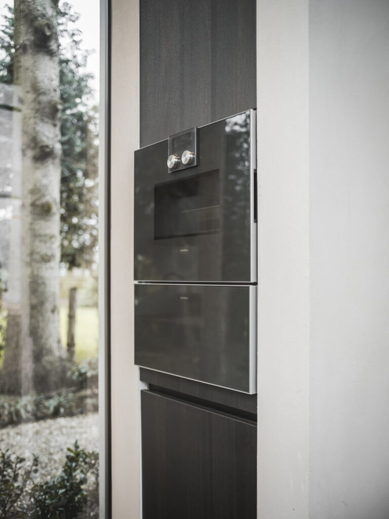 Gaggenau ovens ingebouwd in een donkere kastenwand naast het raam